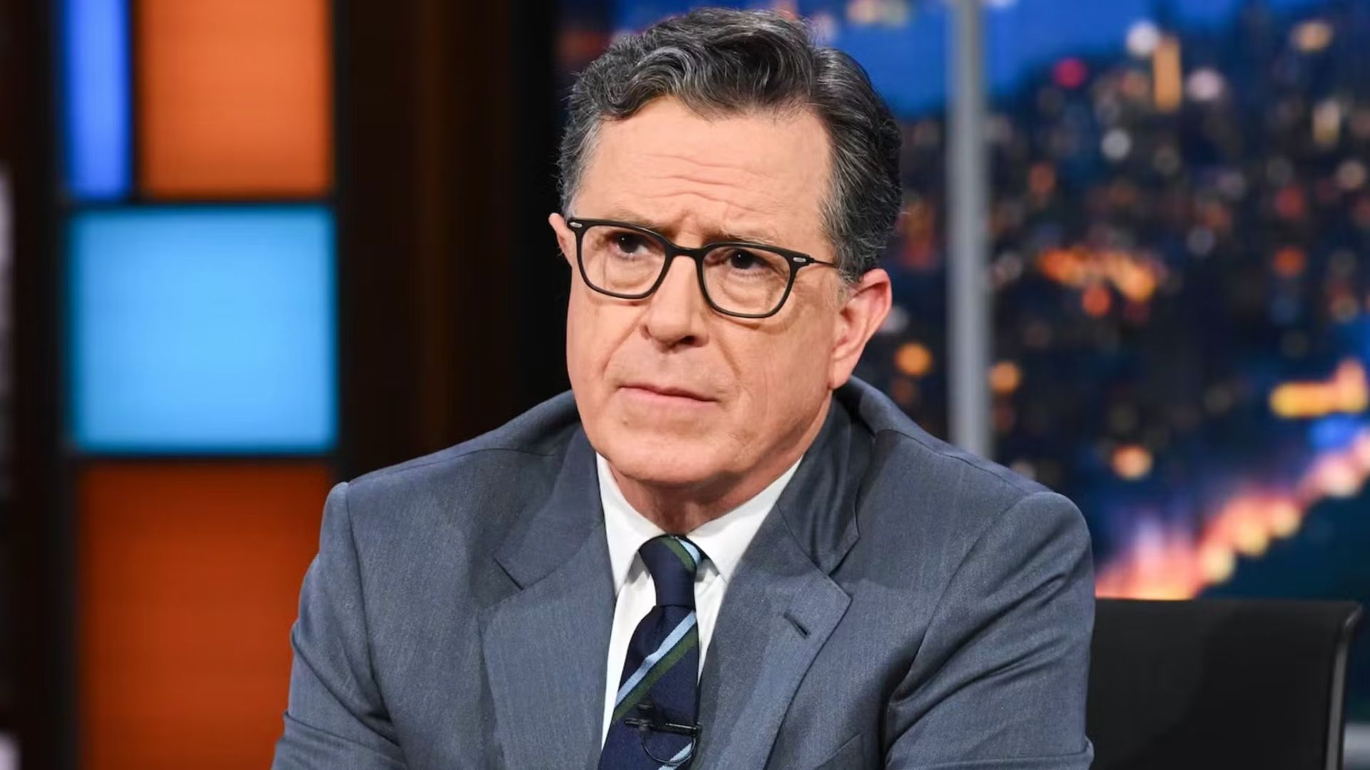 Stephen Colbert sitting at his desk on The Late Show