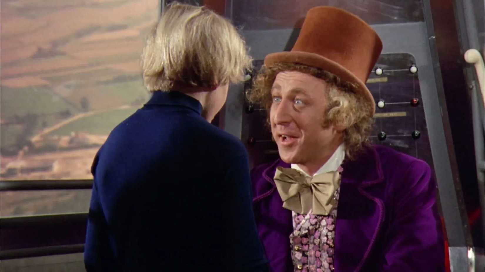Willy Wonka conversando com Charlie Bucket no elevador de vidro gigante.