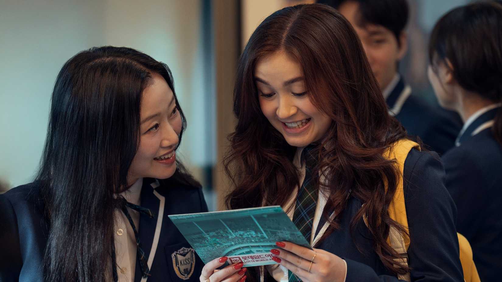 XO Kitty still featuring Kitty and Yuri looking at a photo from a theme park in their KISS uniforms.