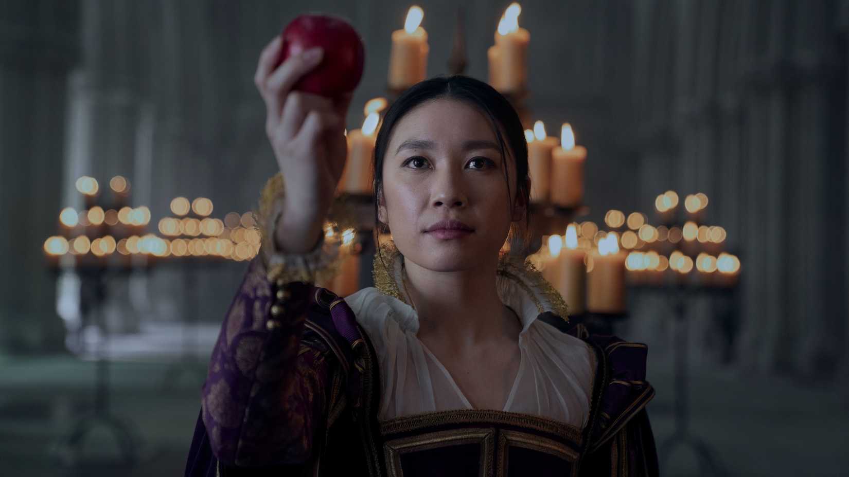 3 Body Problem still featuring Jess Hong as Jin Cheng holding an apple in front of an altar of candles.