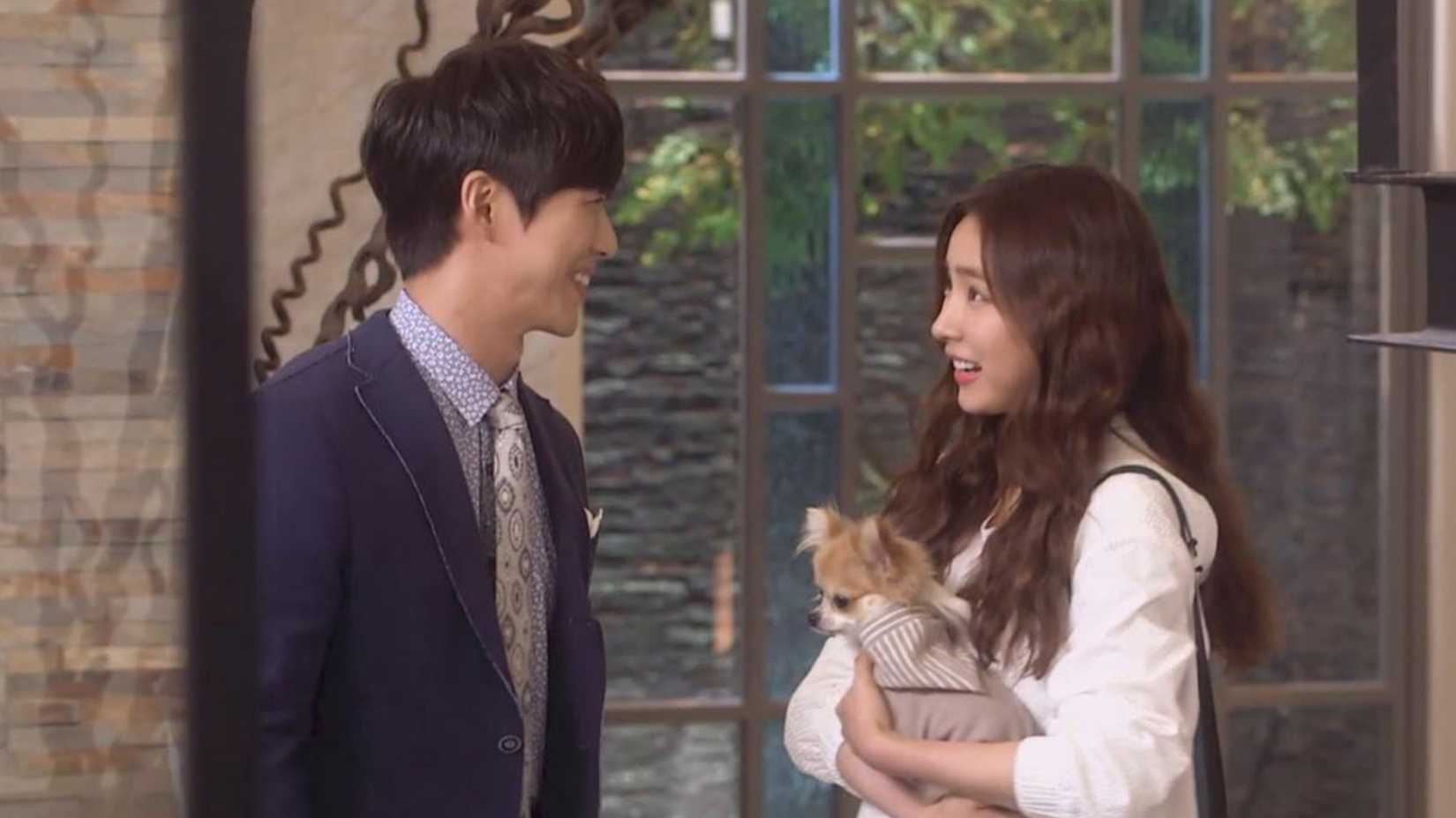 A woman holding a dog and talking to a man in the K-drama A Girl Who Sees Smells.