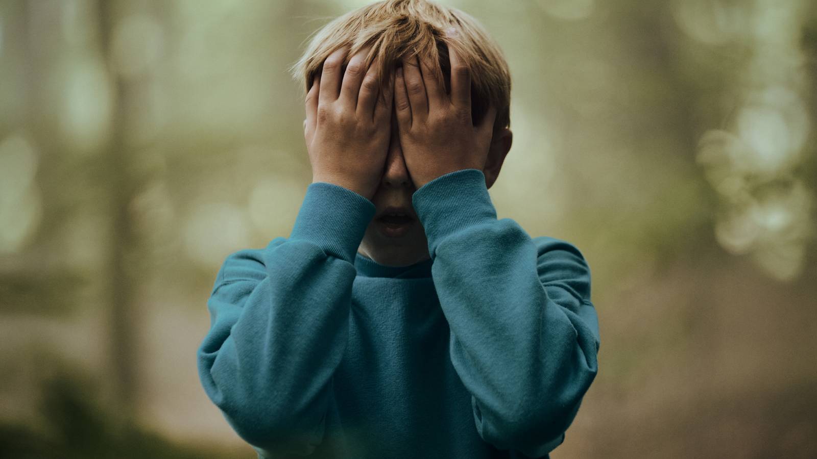 A kid with his hands covering his eyes in The Chestnut Man: Hide and Seek