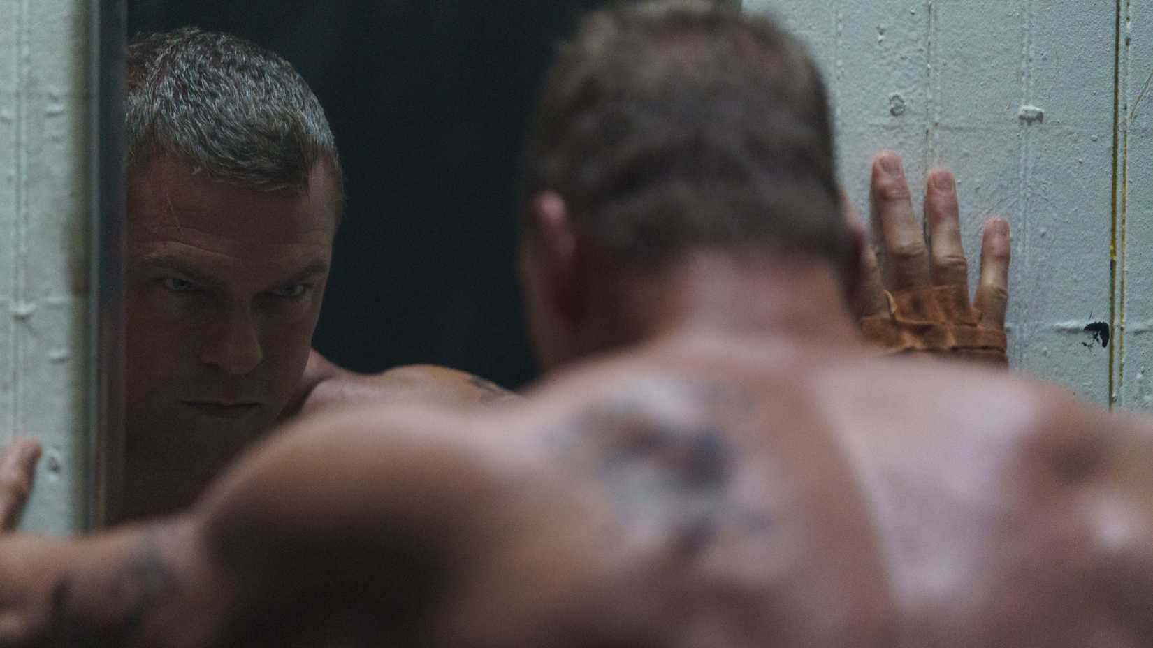 Alan Ritchson looking at himself in the mirror in Motor City