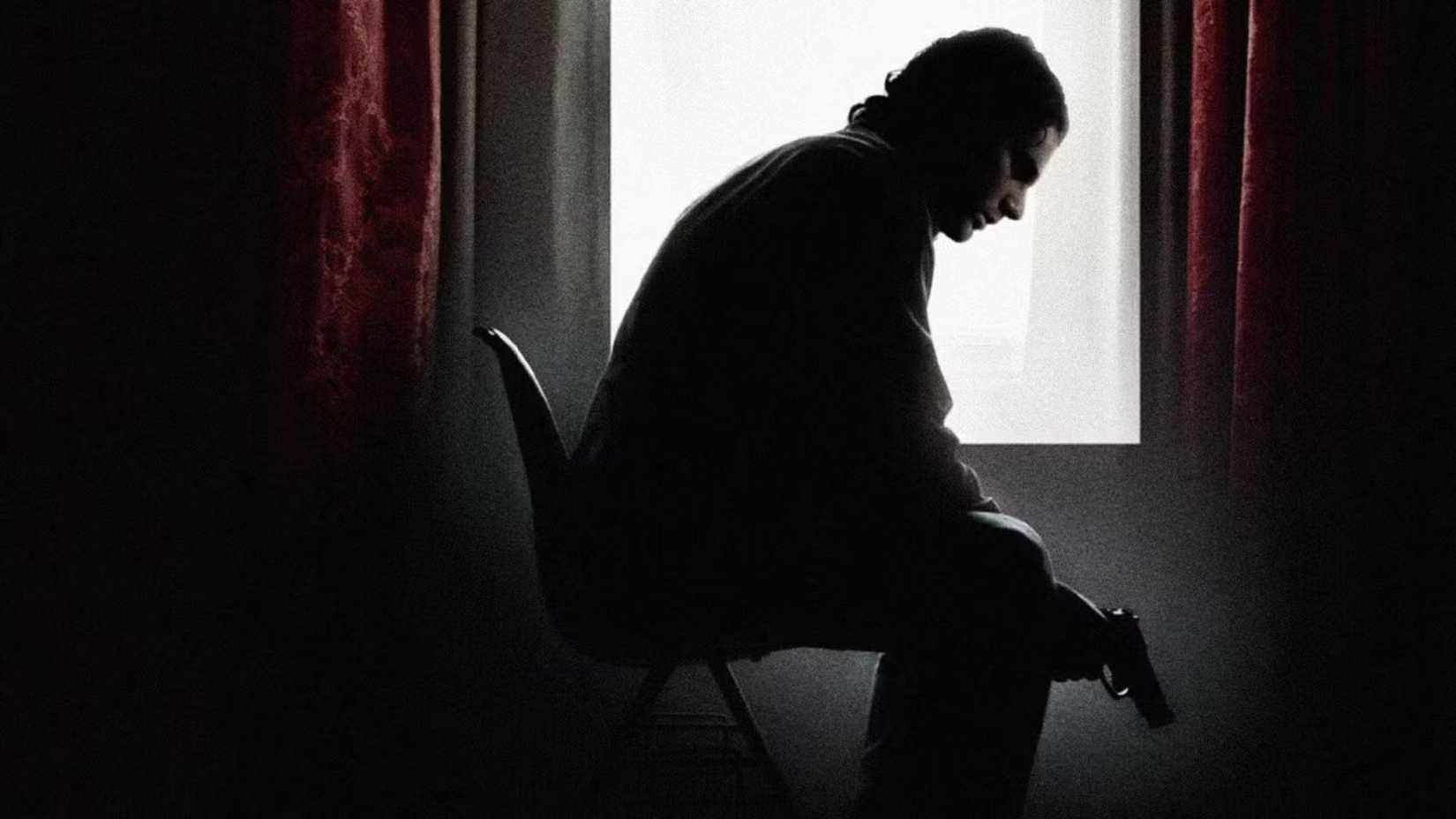 Avner (Eric Bana) sitting on a chair holding a gun in Munich