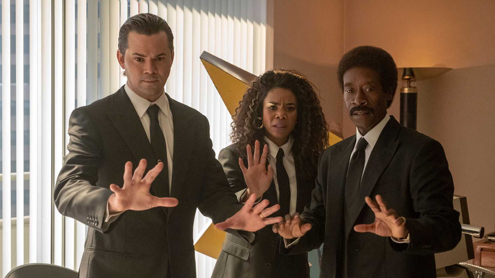 Black Monday's Dawn, Mo, and Blair in suits holding their hands up in front of them. 