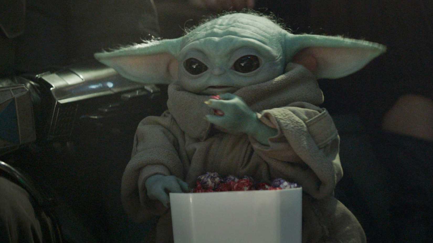 closeup of grogu sitting and eating next to din djarin in the mandalorian and grogu
