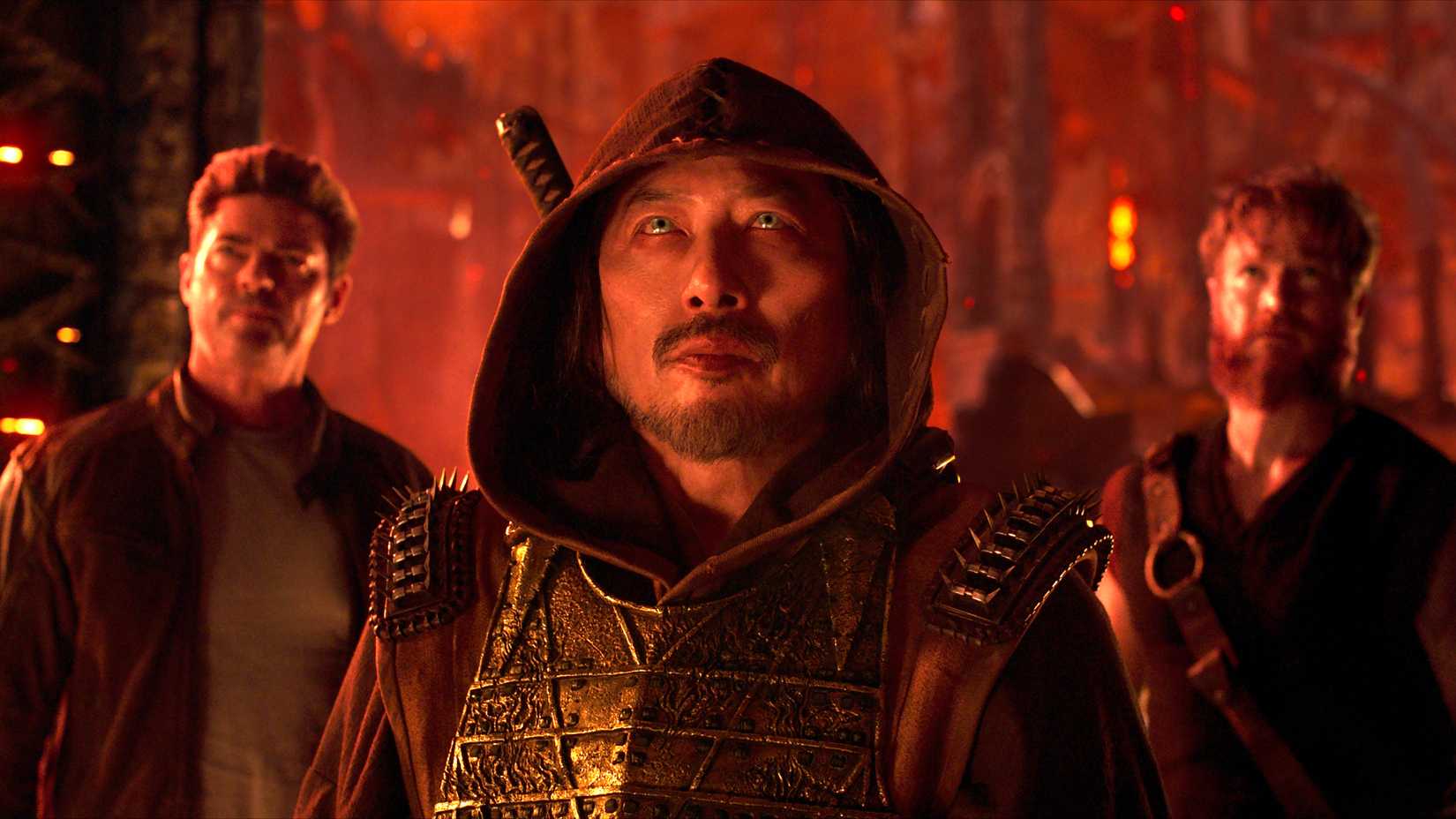 hiroyuki sanada s scorpion standing in front of karl urban s johnny and josh lawson s kano looking up at something in the netherrealm in mortal kombat ii