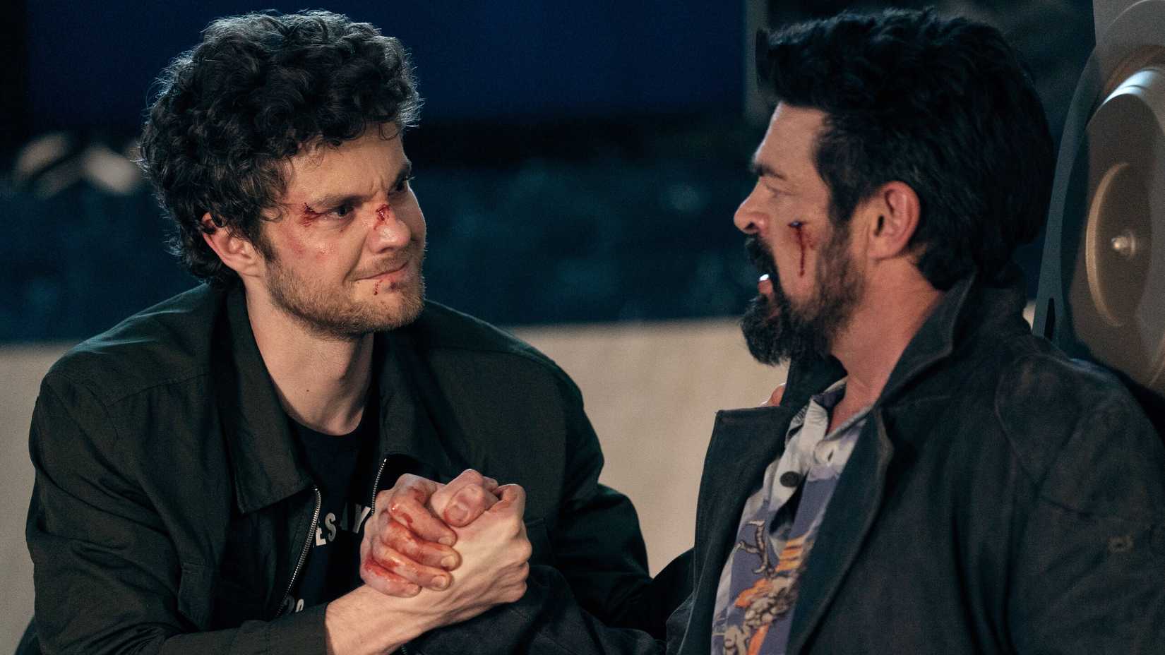 Hughie (Jack Quaid) looking emotional while holding Billy Butcher's (Karl Urban) hand in The Boys season 5