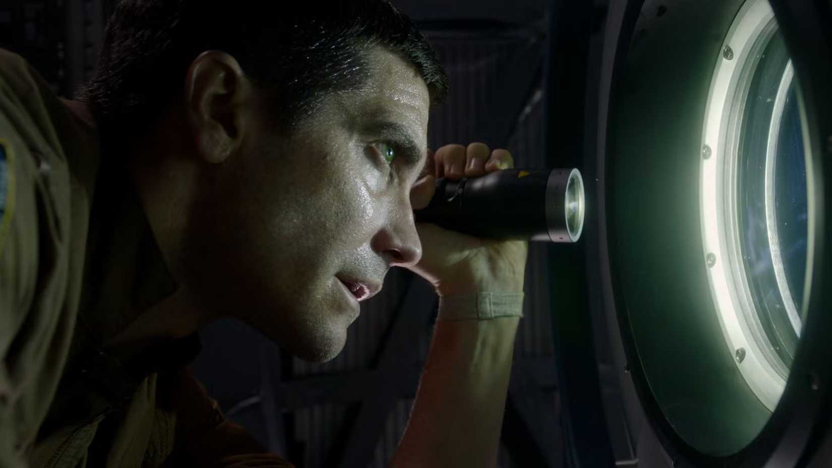 Jake Gyllenhaal shining a flashlight through a window as David Jordan in Life