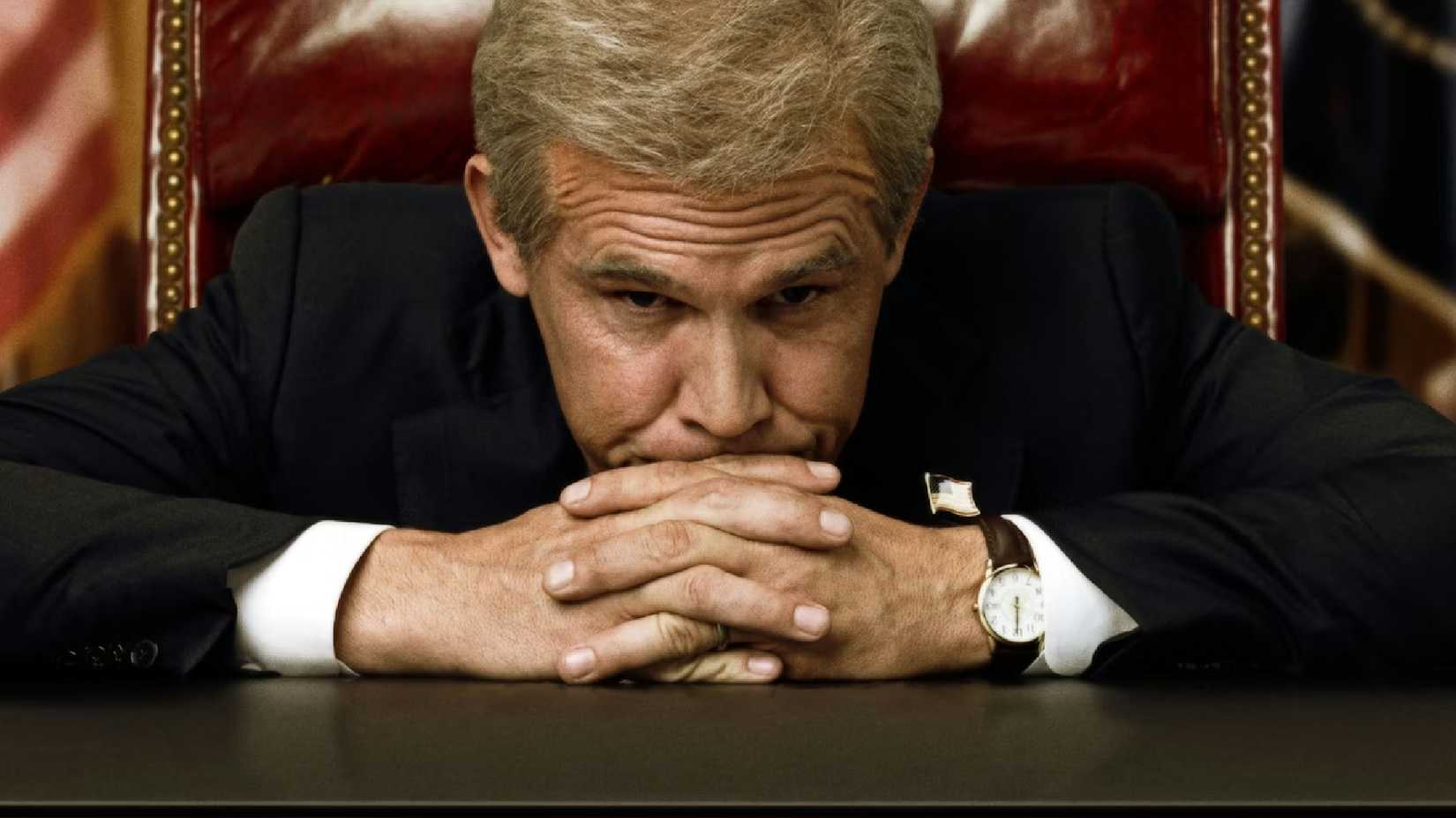 Josh Brolin leans against his desk as George W Bush in W