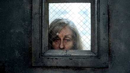 Dorry de Judith Light mirando a través de la ventana de la puerta plateada con sangre en los ojos en The Terror: The Devil in Silver