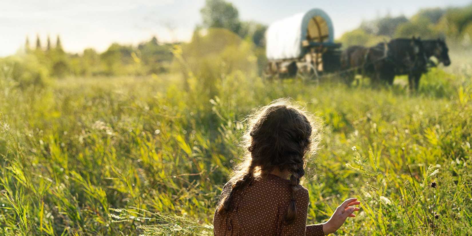 laura sitting in a field in little house on the prairie
