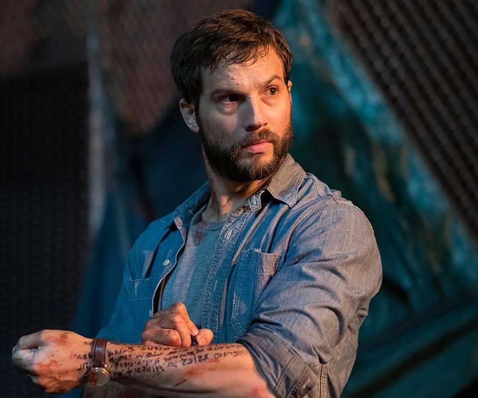 Logan Marshall-Green's Grey looking curiously while writing code on his arm in marker in Upgrade