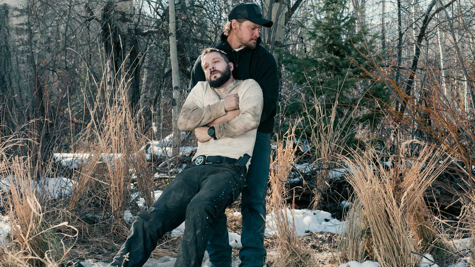 Luke Grimes' Kayce dragging Logan Marshall-Green's Cal through the forest in Marshals season 1