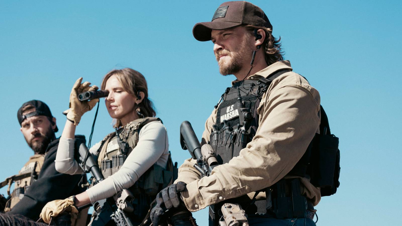 Logan Marshall-Green's Cal and Luke Grimes' Kayce looking intently at someone while holding their rifles in Marshals season 1
