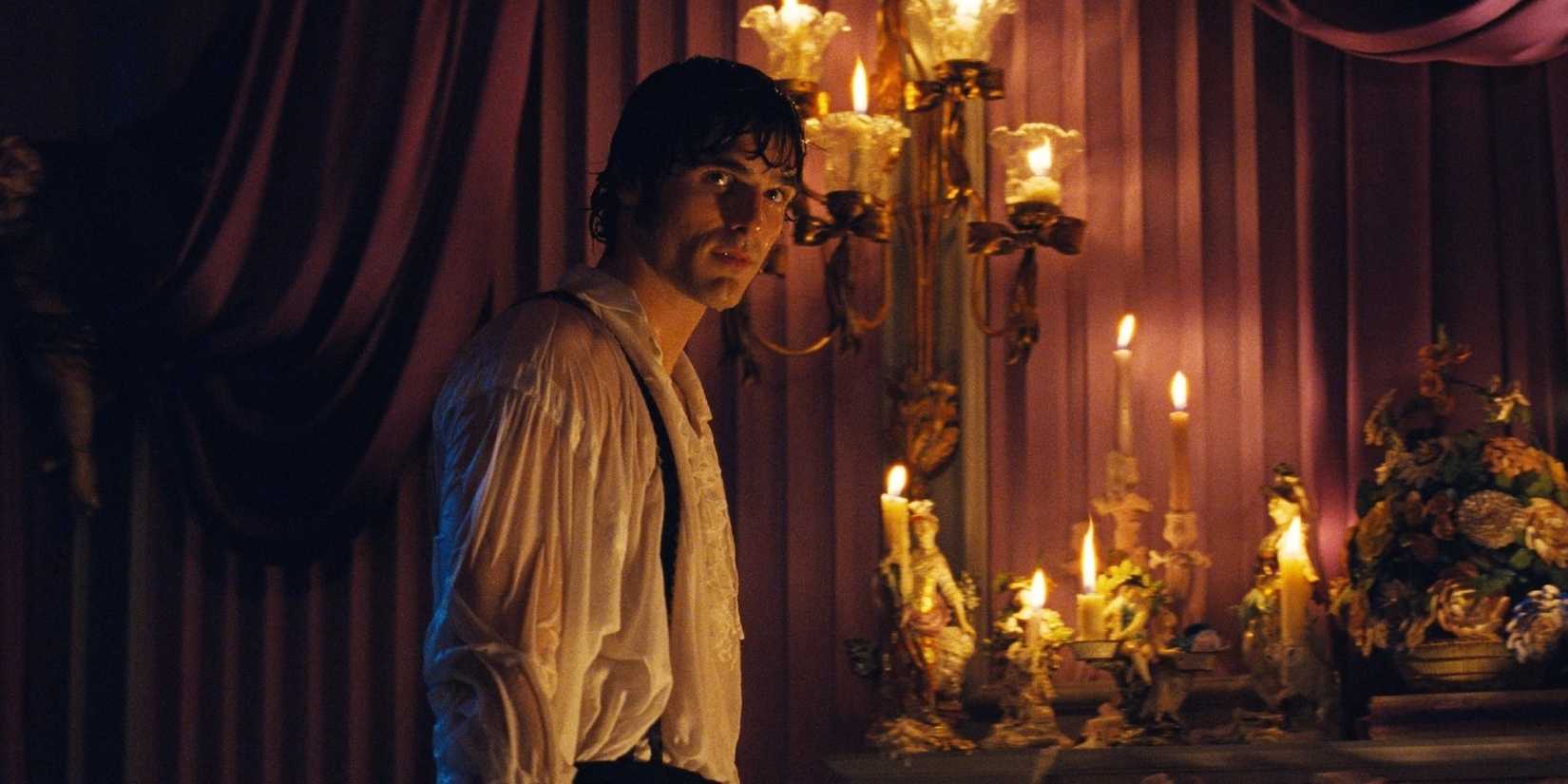 Jacob Elordi standing in front of candles in Wuthering Heights.