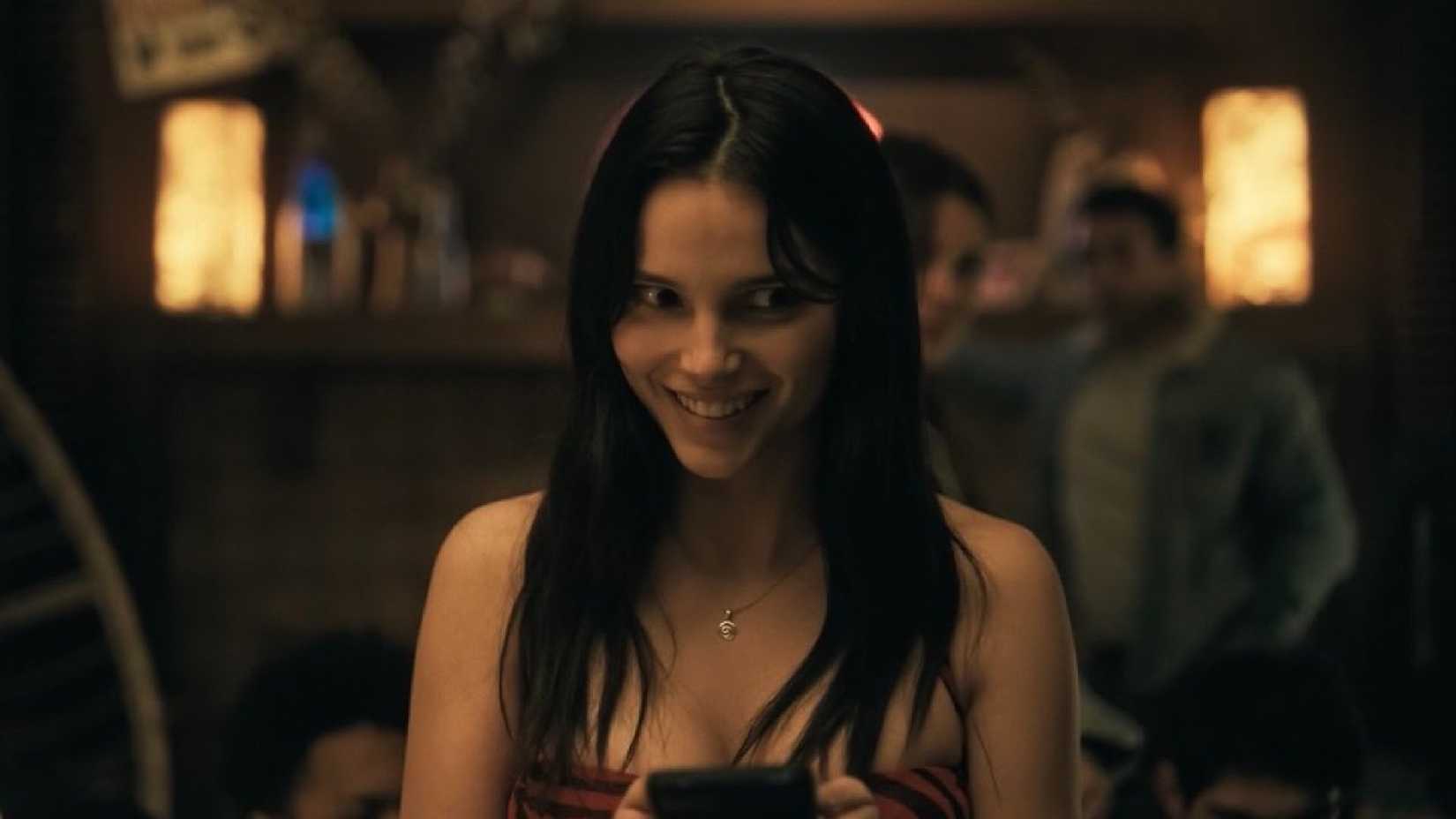 Nikki em cena do filme Obsession segurando um celular.
