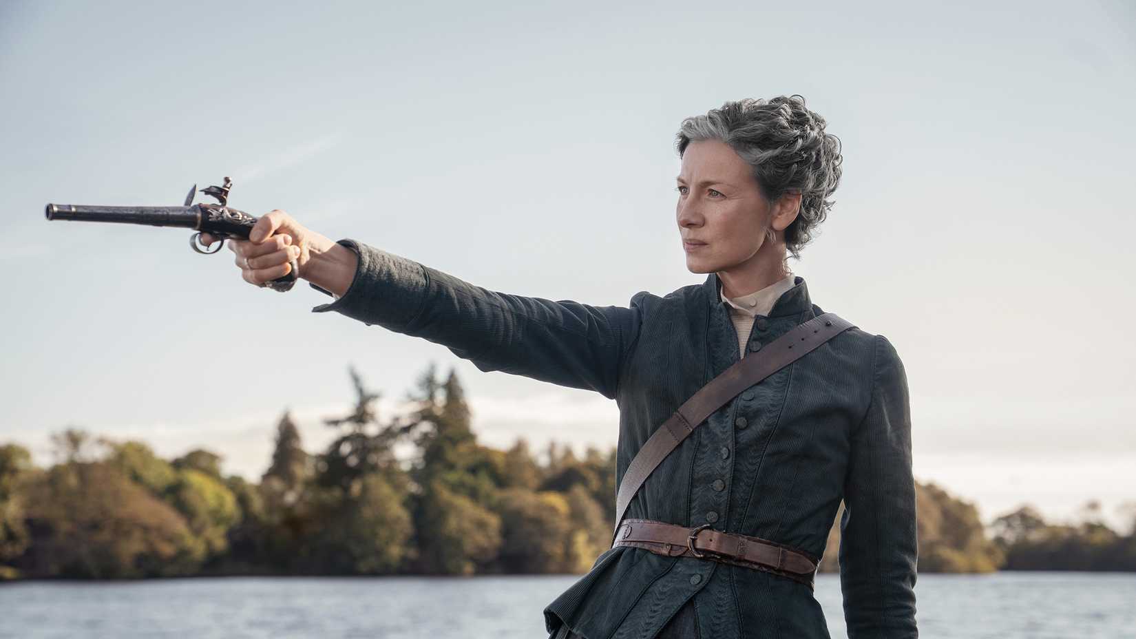 Claire holding up a gun in Outlander season 8
