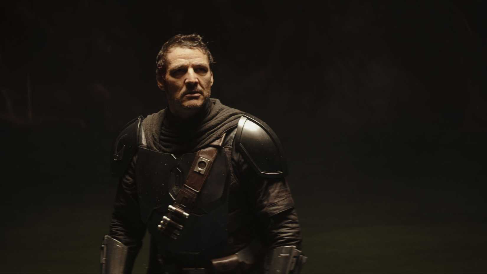 pedro pascal as din djarin without his helmet standing in a cave in the mandalorian and grogu
