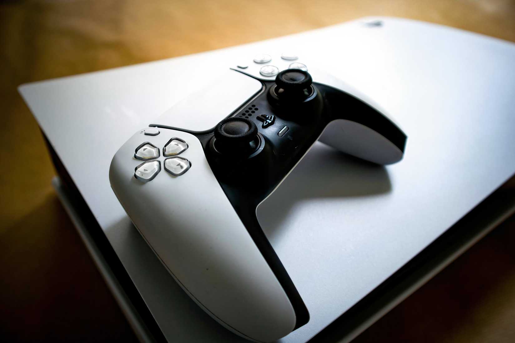 Detailed shot of a PlayStation 5 controller resting on the console, highlighting modern gaming design.