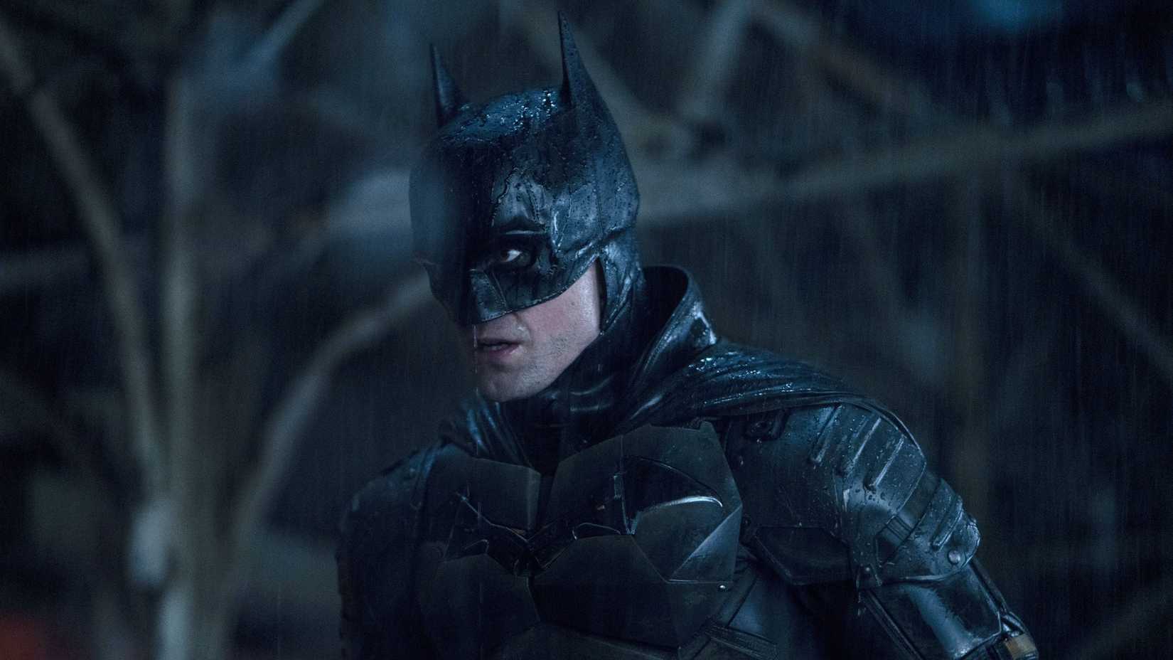 robert pattinson as batman standing in the rain in the batman