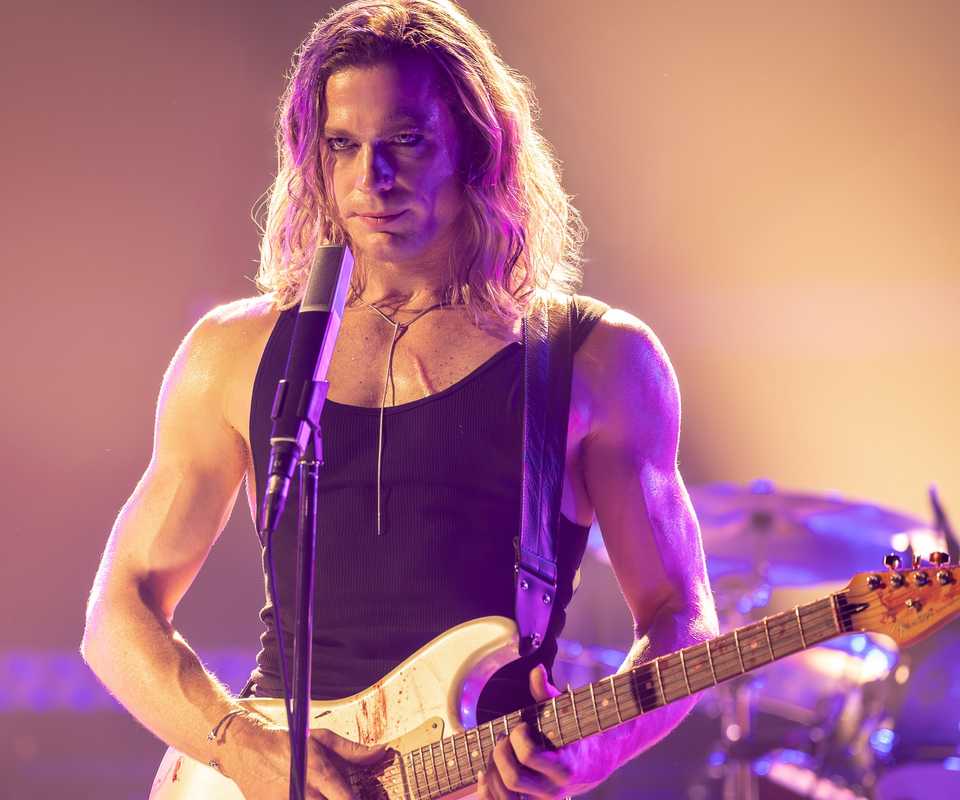 Sam Reid as Lestat on stage with a guitar in The Vampire Lestat