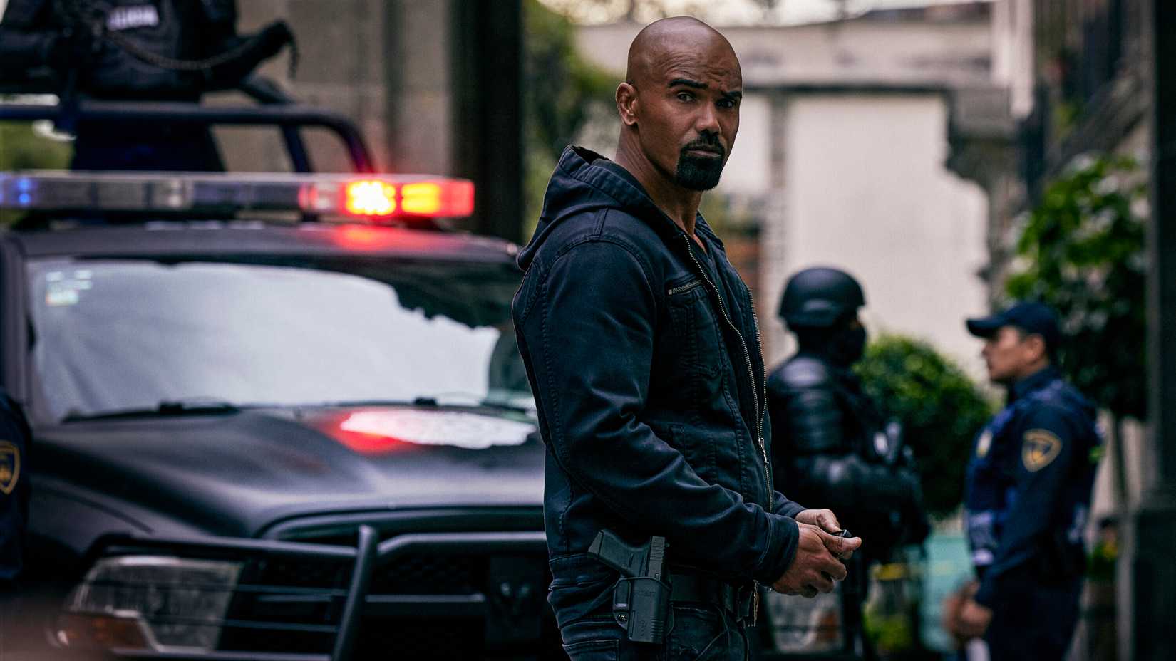 SWAT still featuring Shemar Moore as Hondo standing in front of Black Betty in a zip up hoodie.