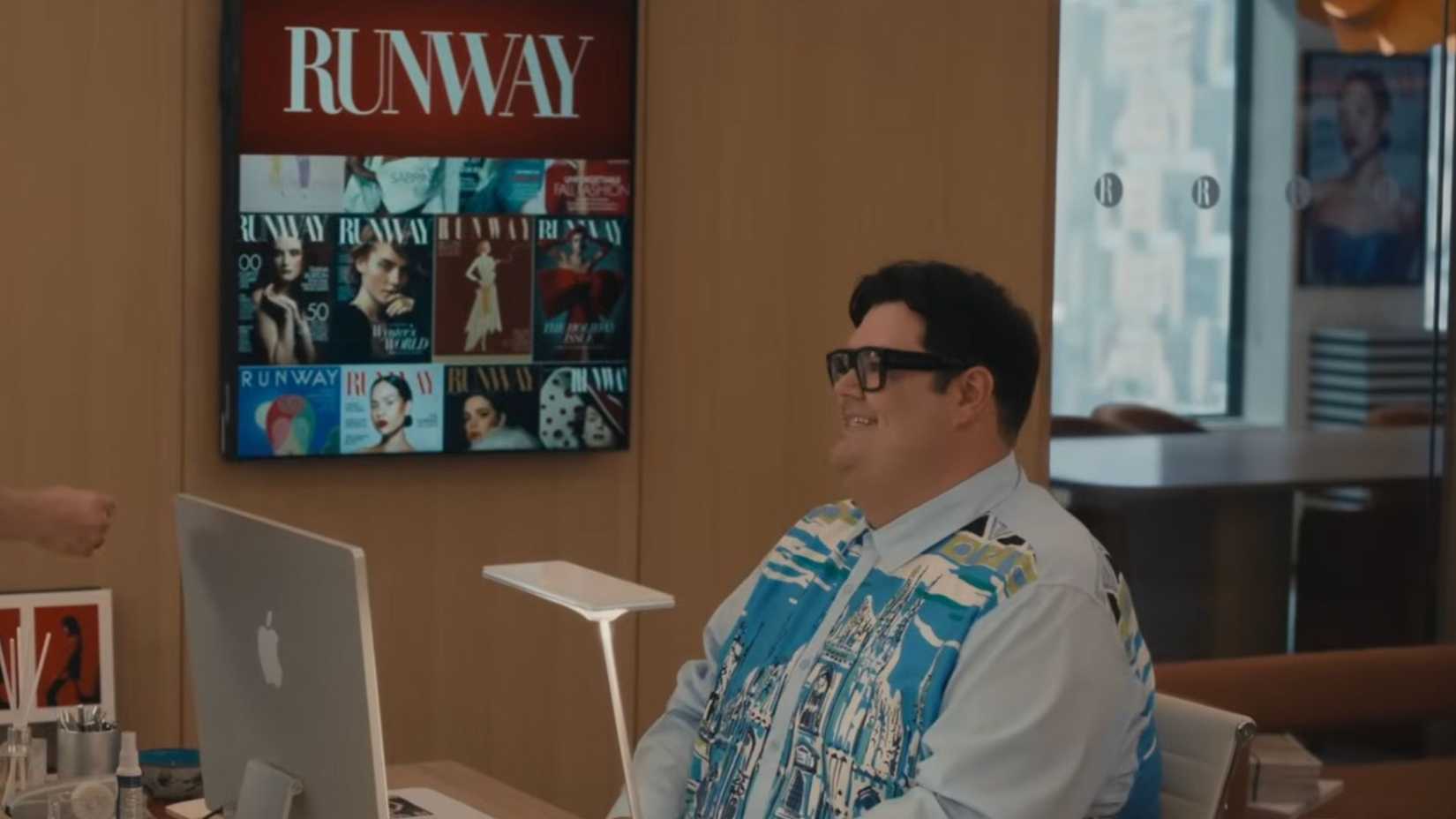 Charlie sentado em sua mesa com uma camisa vibrante