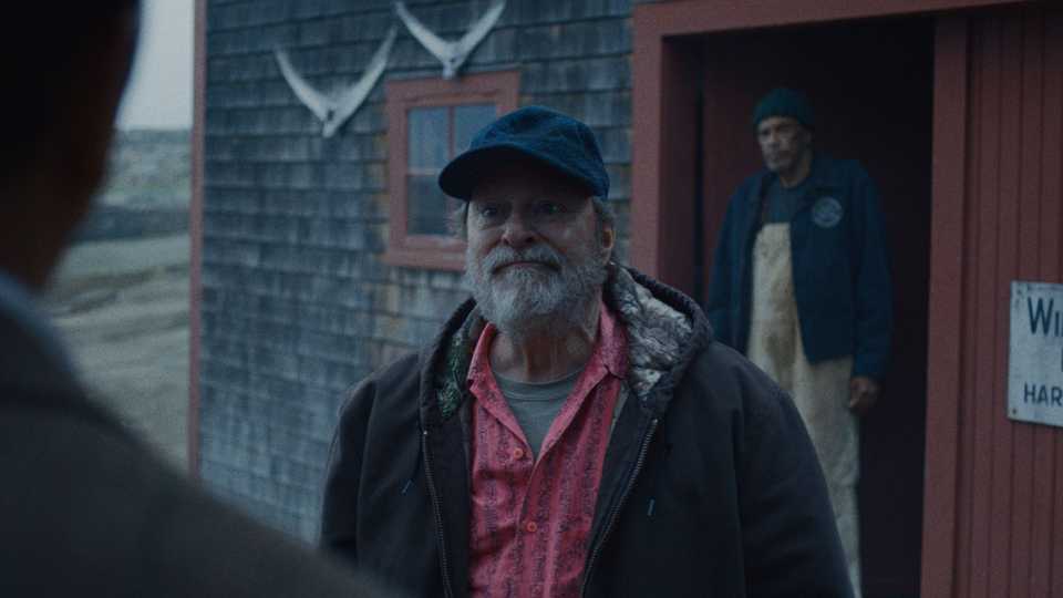 Wyck (Stephen Root) standing outside a fishing shack in Widow's Bay.