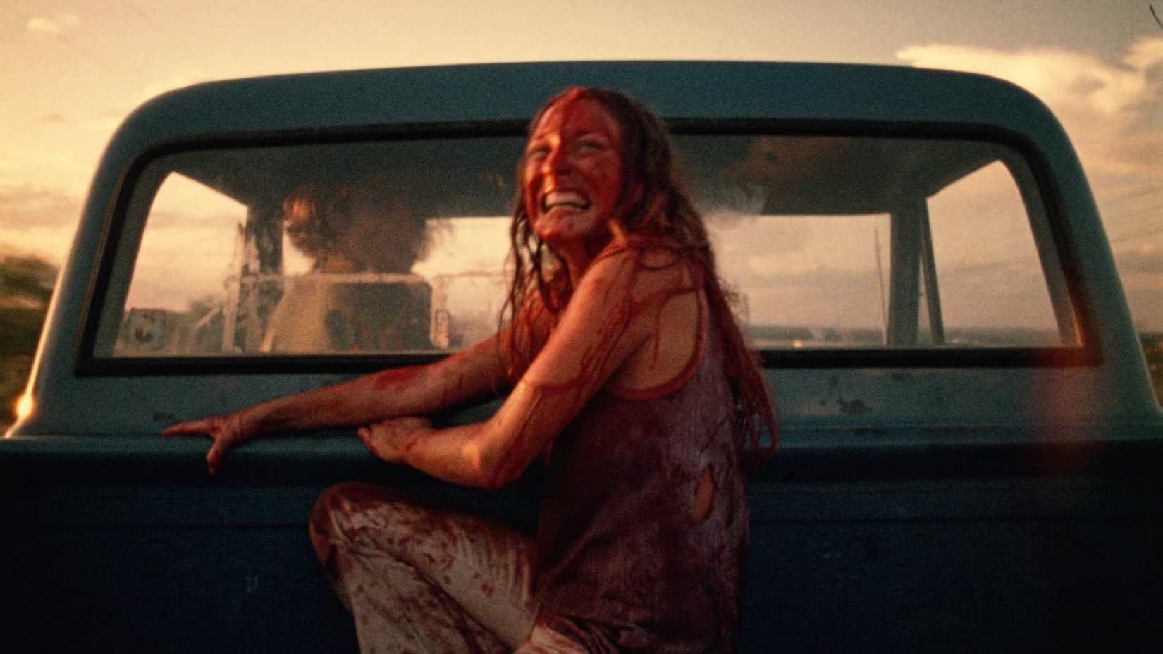Sally Hardesty is covered in blood and laughs as she rides off in the back of a truck in The Texas Chain Saw Massacre (1974)