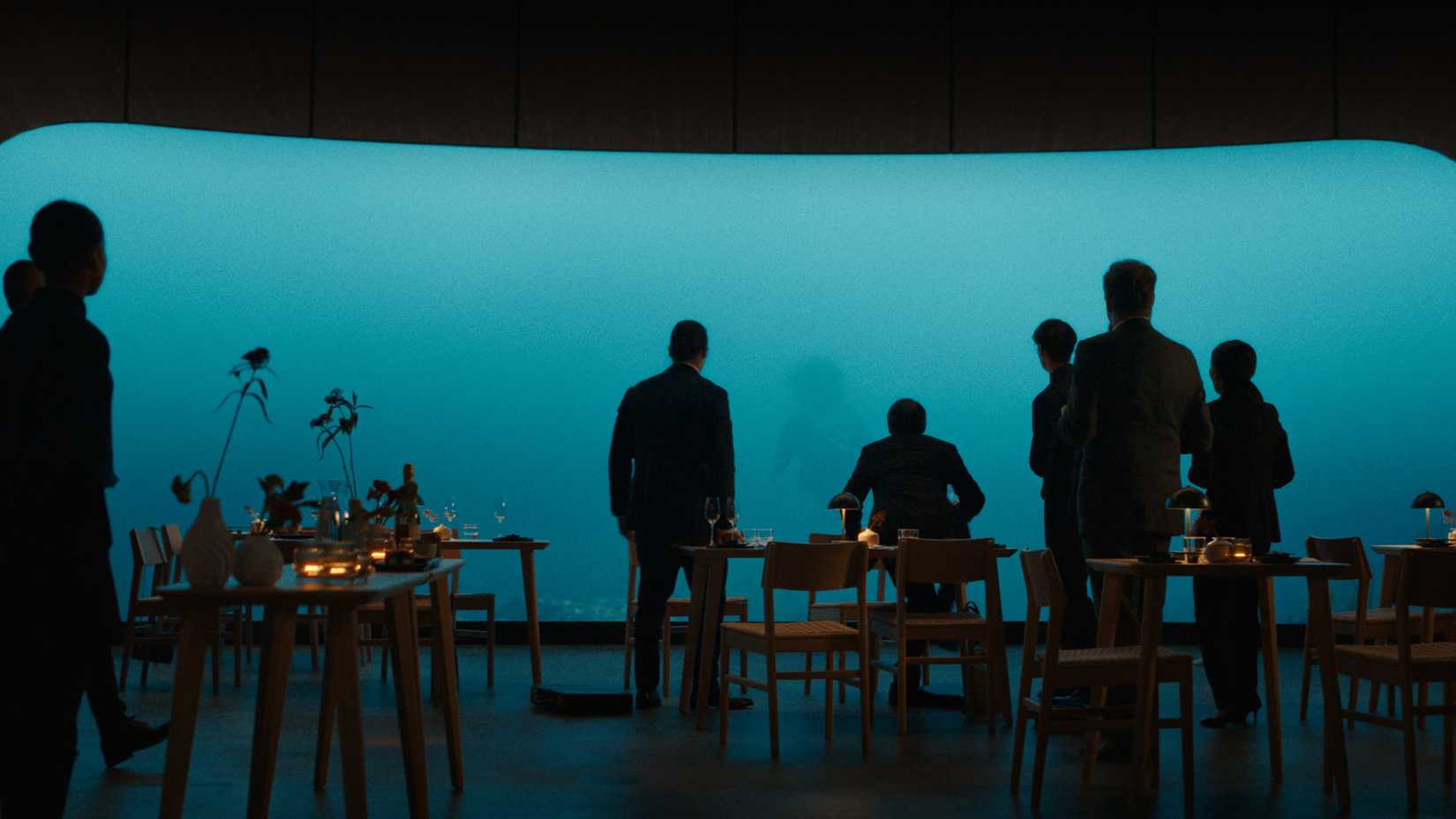 A group of people looking at a dead body through an underwater glass window in Kraken