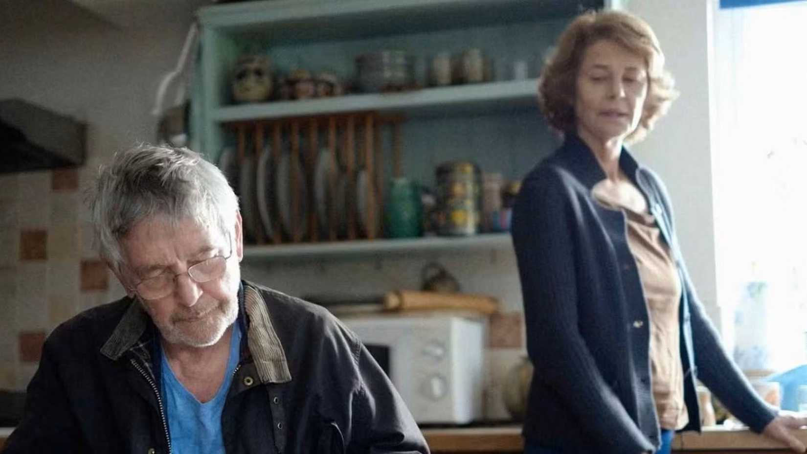 A woman looking at man while he reads at a table in 45 Years.