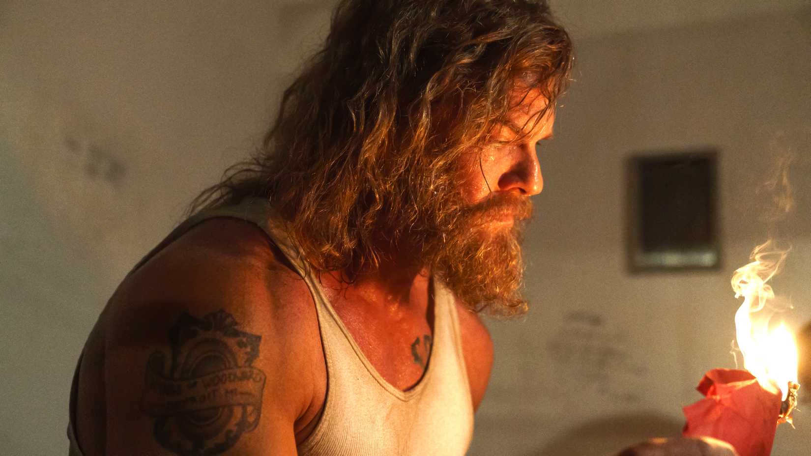 Alan Ritchson's John holding a paper burning in Motor City