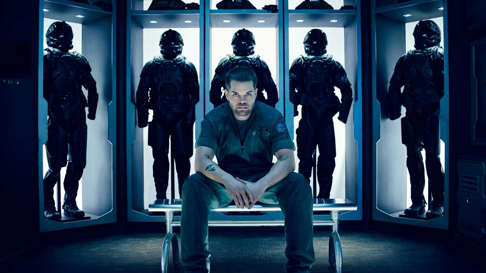 עמוס יושב מול חליפות חלל ב-The Expanse