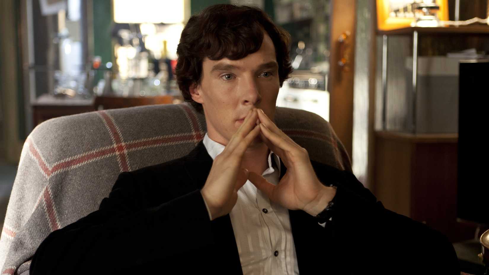 Benedict Cumberbatch as Sherlock Holmes sitting in a chair with his fingers steepled against his mouth in Sherlock season 2, episode 3