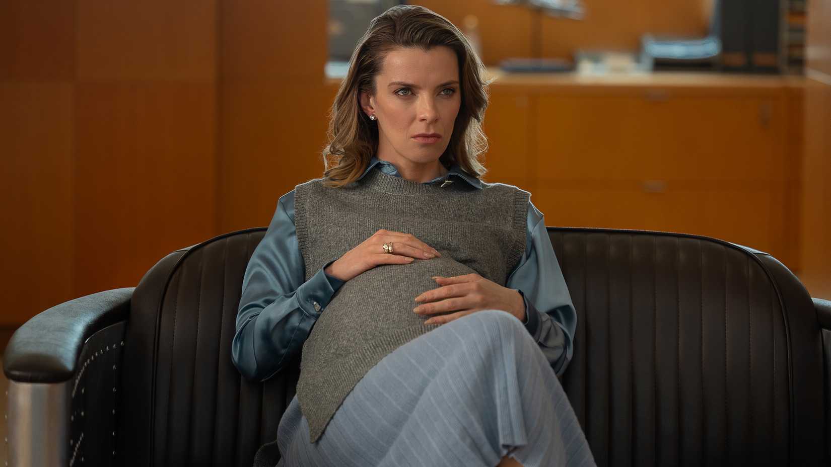 Betty Gilpin's Sydney looking intensely while sitting with her hand on her pregnant stomach in Office Romance