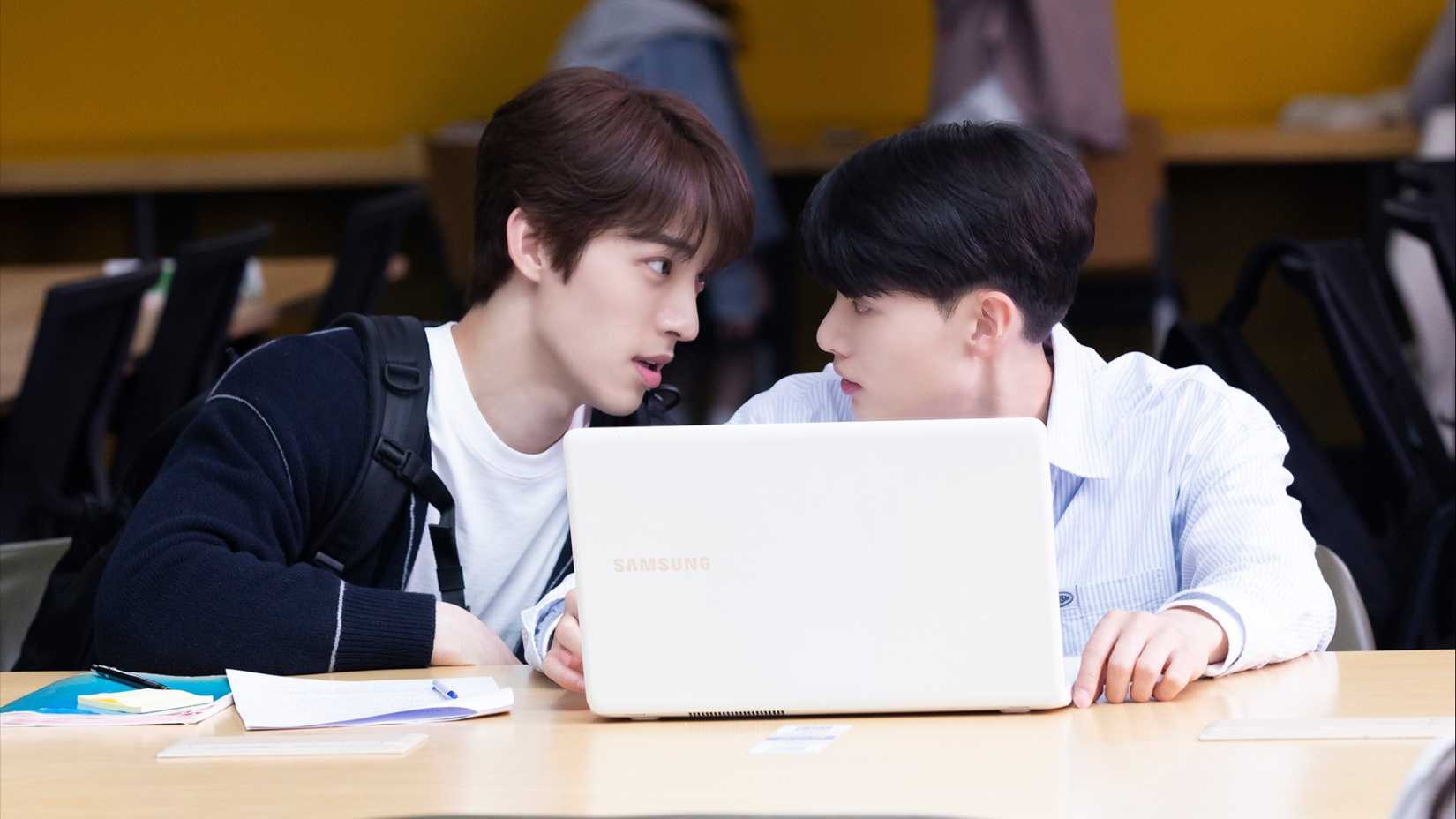 Two students hunched over a laptop in the K-drama Blueming.