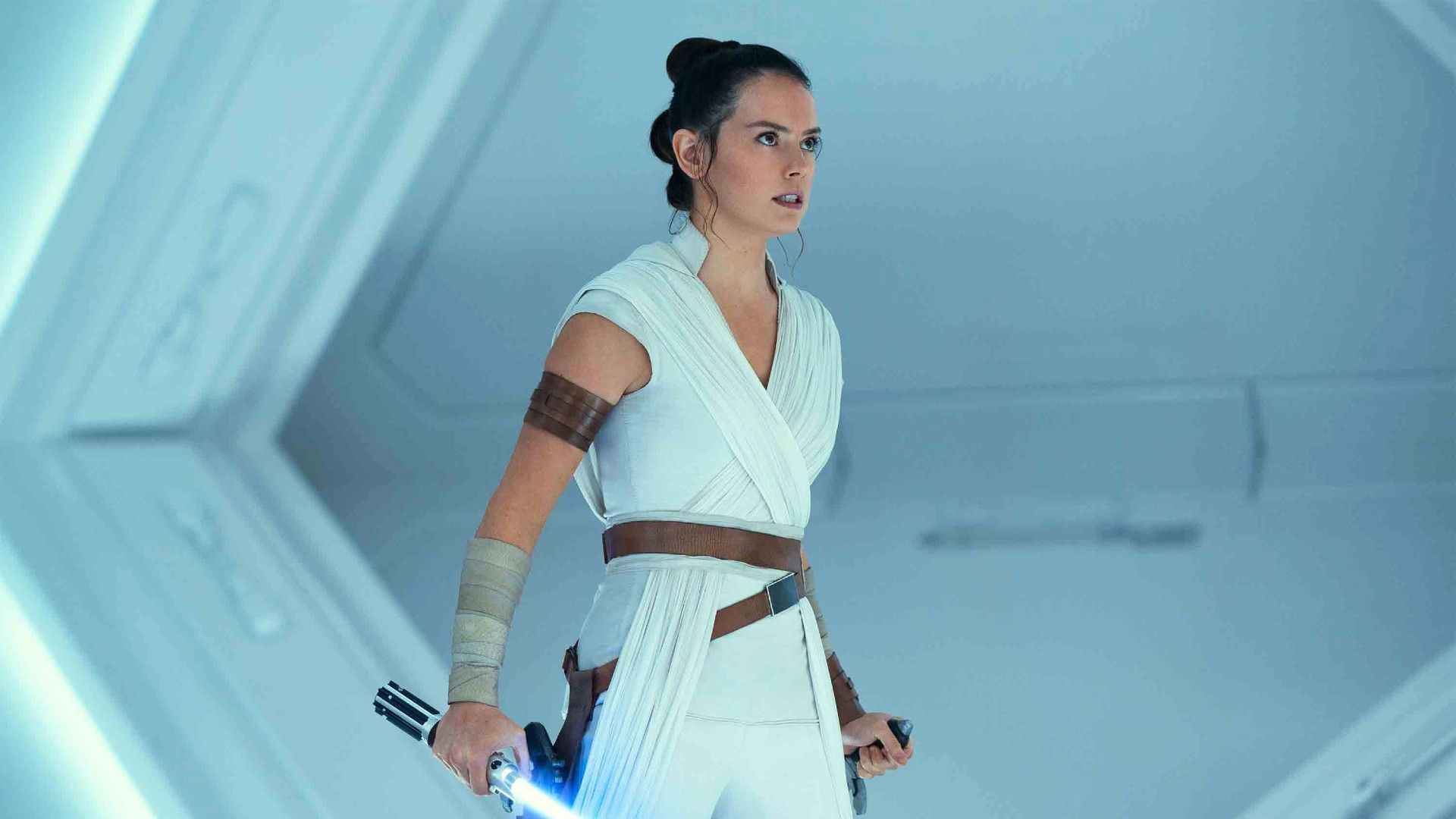 Daisy Ridley as Rey in Star Wars The Rise of Skywalker holding Anakin's lightsaber