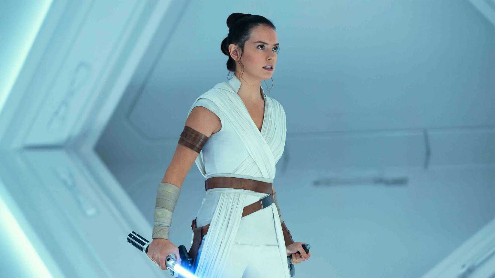 Daisy Ridley as Rey in Star Wars The Rise of Skywalker holding Anakin's lightsaber