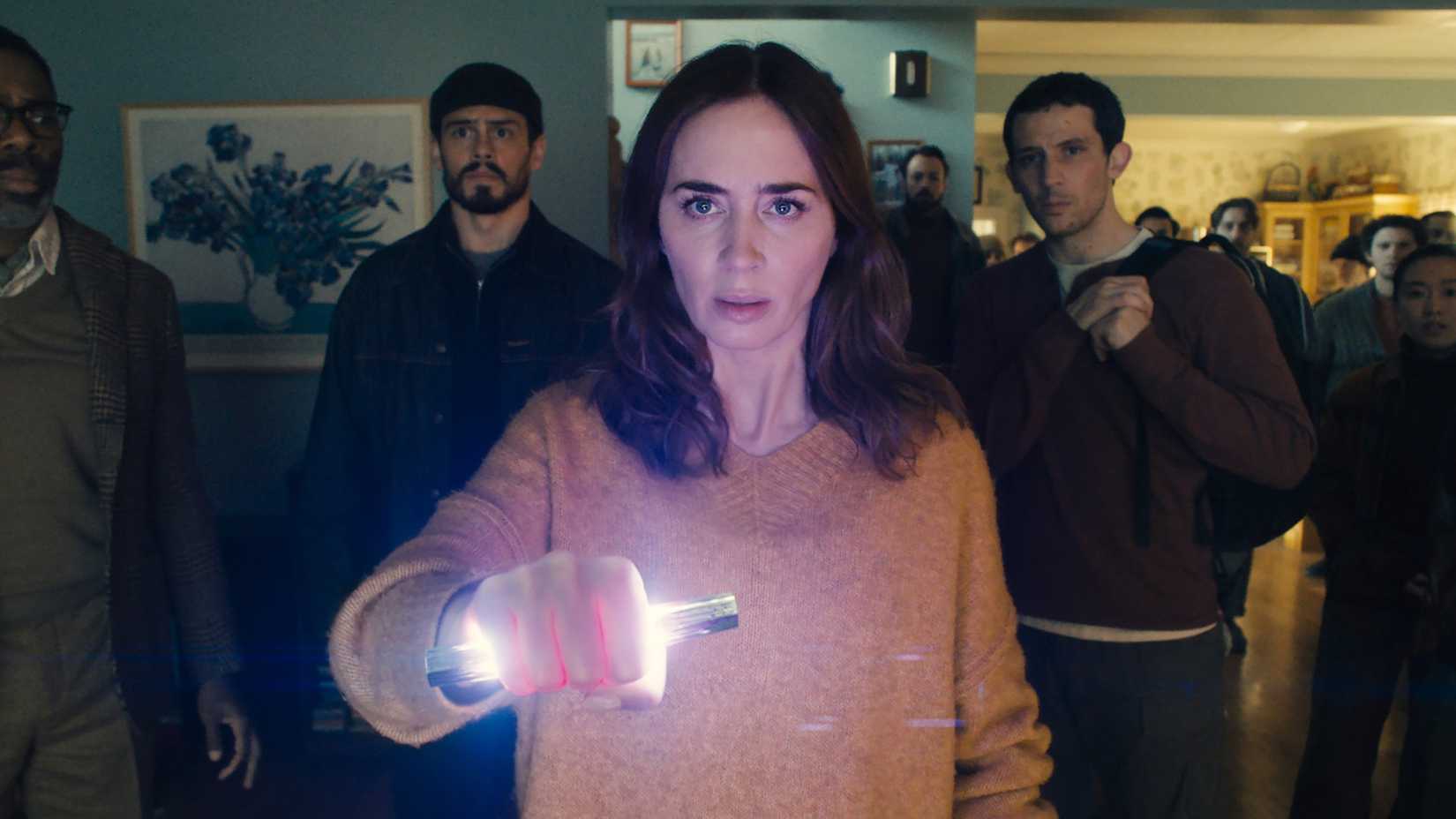 Emily Blunt's Margaret holding a glowing piece of alien technology while a group of people stand behind her looking worried in Disclosure Day
