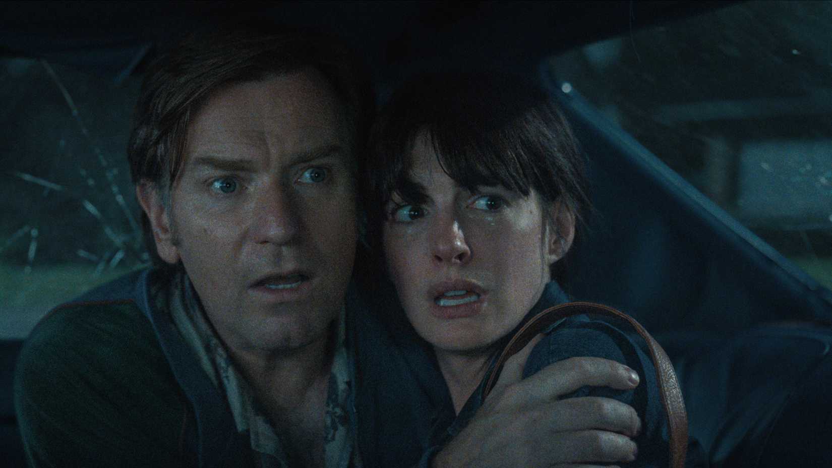 Ewan McGregor and Anne Hathaway cower in fear in the back of a car in The End of Oak Street Trailer