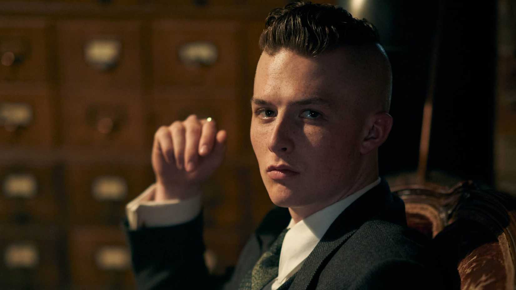 Finn Shelby has slicked back hair and looks at the camera in Peaky Blinders season 6