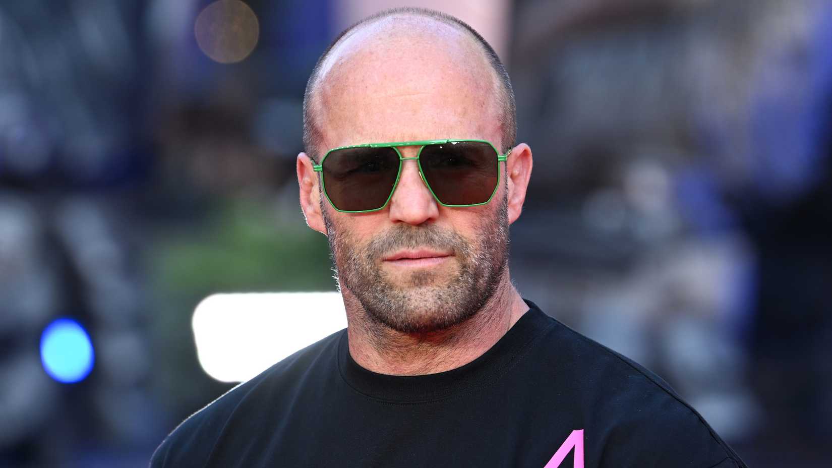 Jason Statham looks straight forward with a serious expression while attending an event