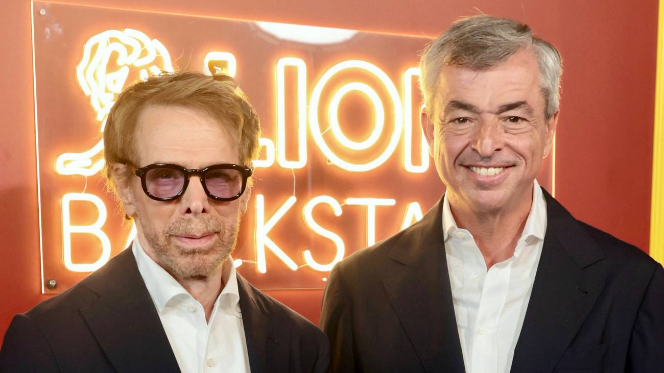 Jerry Bruckheimer and Eddy Cue together in front of a Cannes Lions neon sign