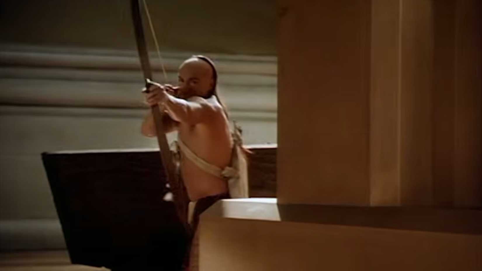 Little Bear firing a bow and arrow around a corner in The Indian in the Cupboard