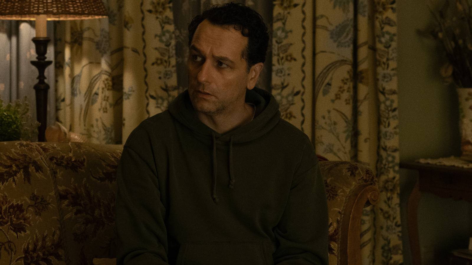 Matthews Rhys as Tom Loftis sitting and looking conflicted in Widow's Bay season 1 finale