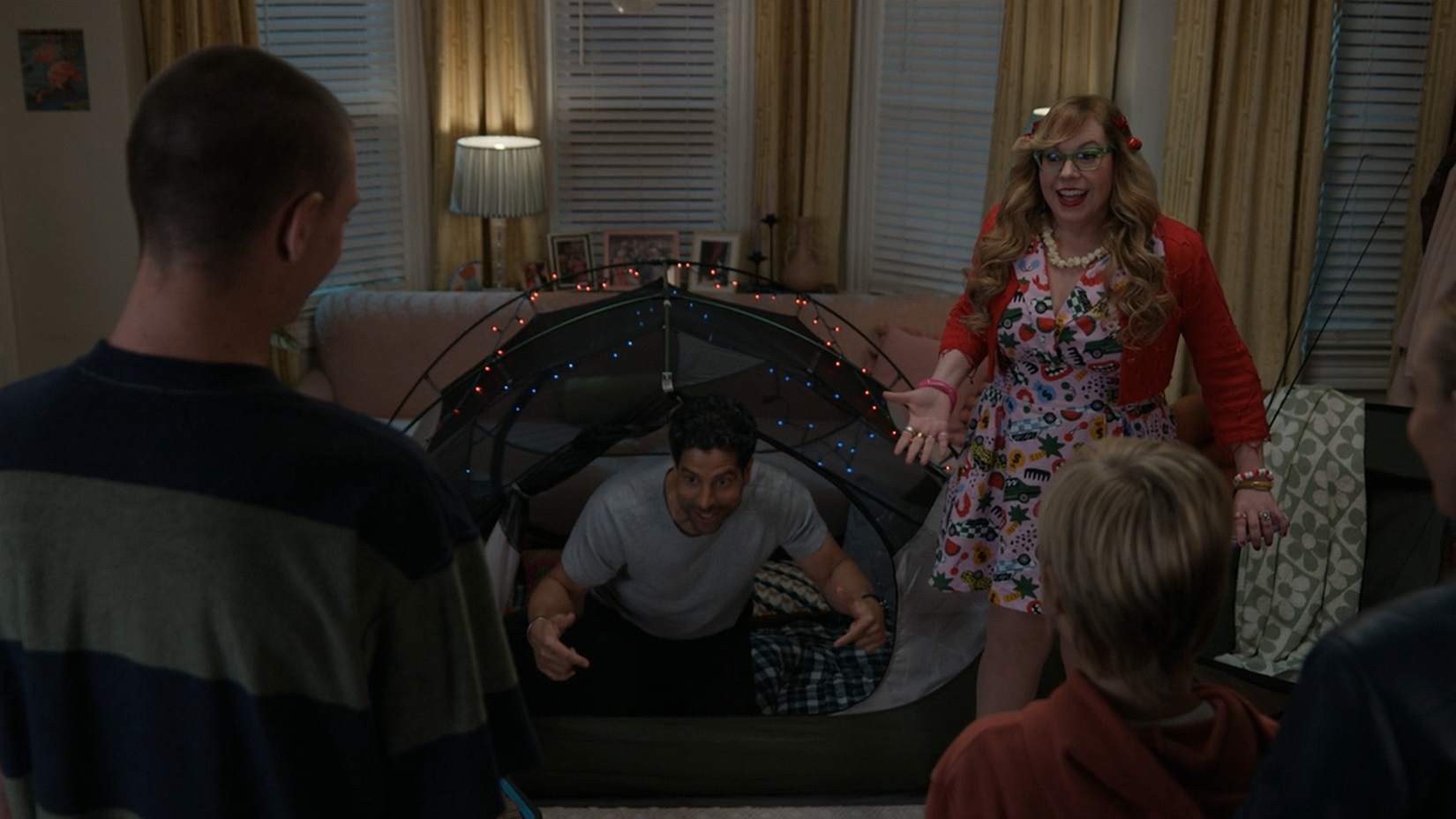 Still from Criminal Minds season 19 episode 3, "Body Count" where Luke Alvez and Penelope Garcia stand in her colorful living room, having set up a tent and string lights for JJ and her kids.