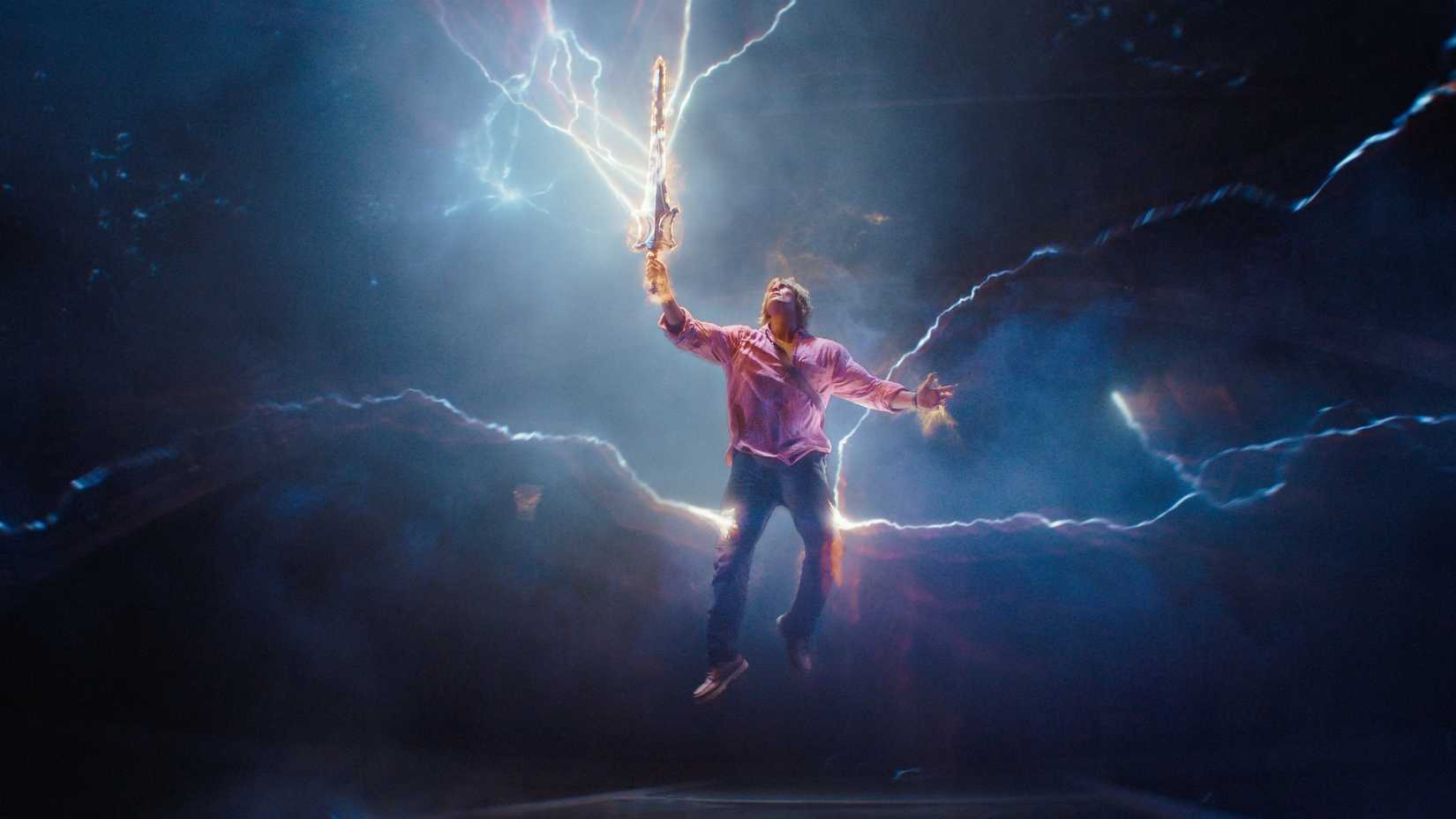Nicholas Galitzine As Adam Holding Up The Sword Of Power As Lightning Strikes In Masters Of The Universe