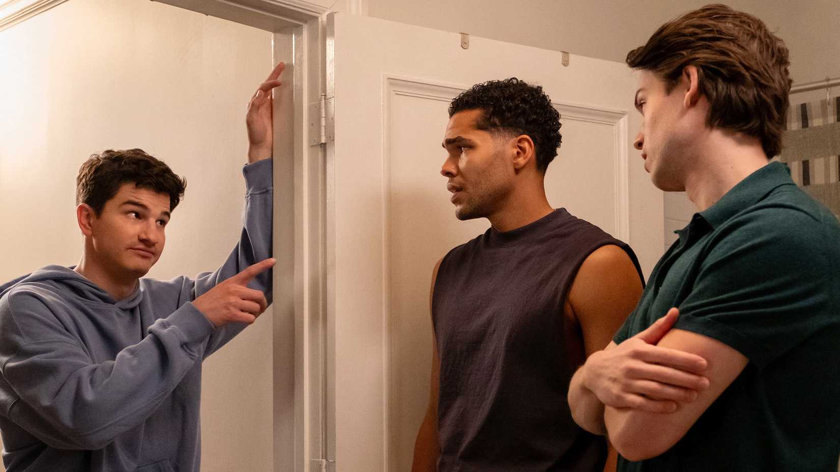 Roommates Davis pointing at Kel with Josh watching in apartment.