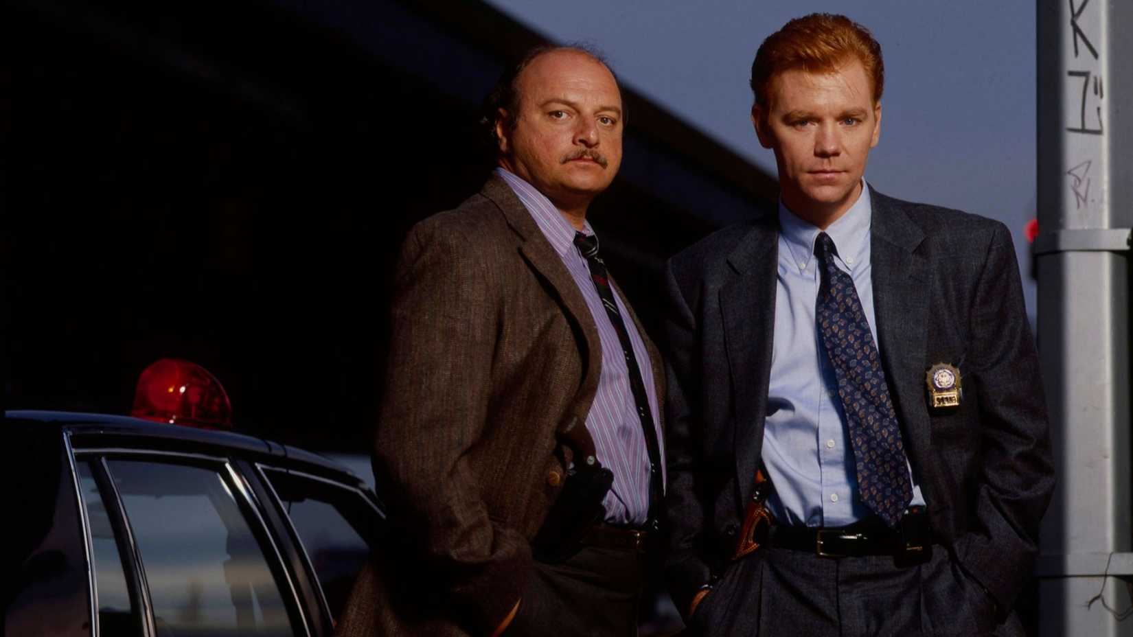 Andy Sipowicz (Dennis Franz) and John Kelly (David Caruso) standing next to one another in NYPD Blue.